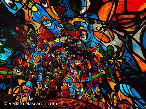 A vibrant and colorful abstract mural featuring various shapes, cartoonish faces, and floral elements, creating a lively and dynamic visual experience.